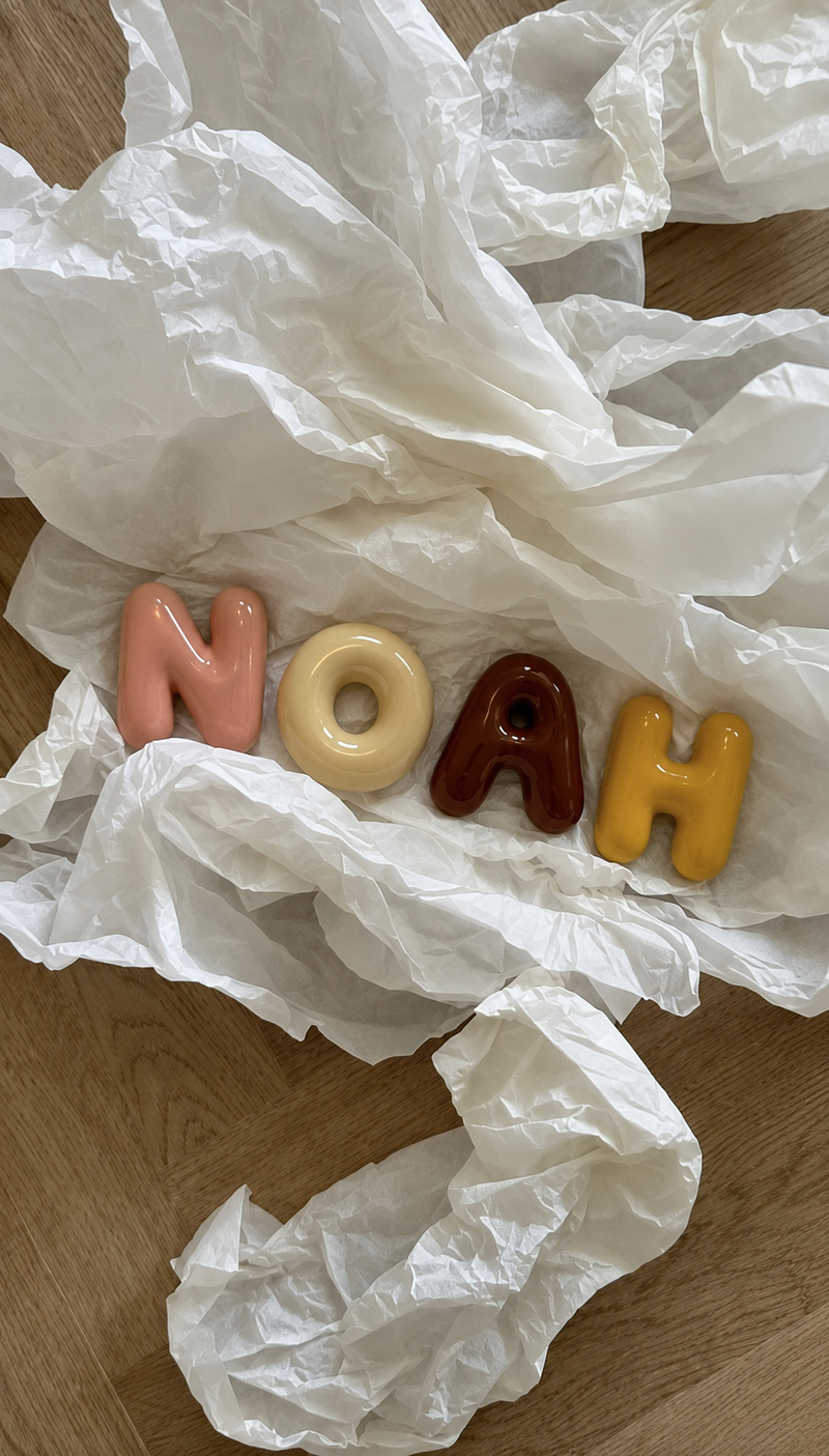 Bubble letters spelling NOAH resting on tissue paper